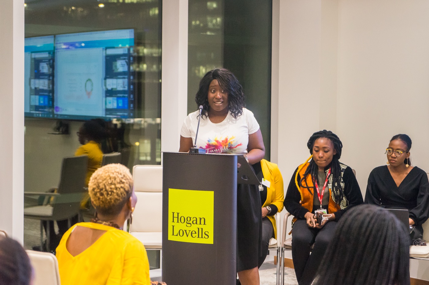 Speaking from a lectern branded Hogan Lovells