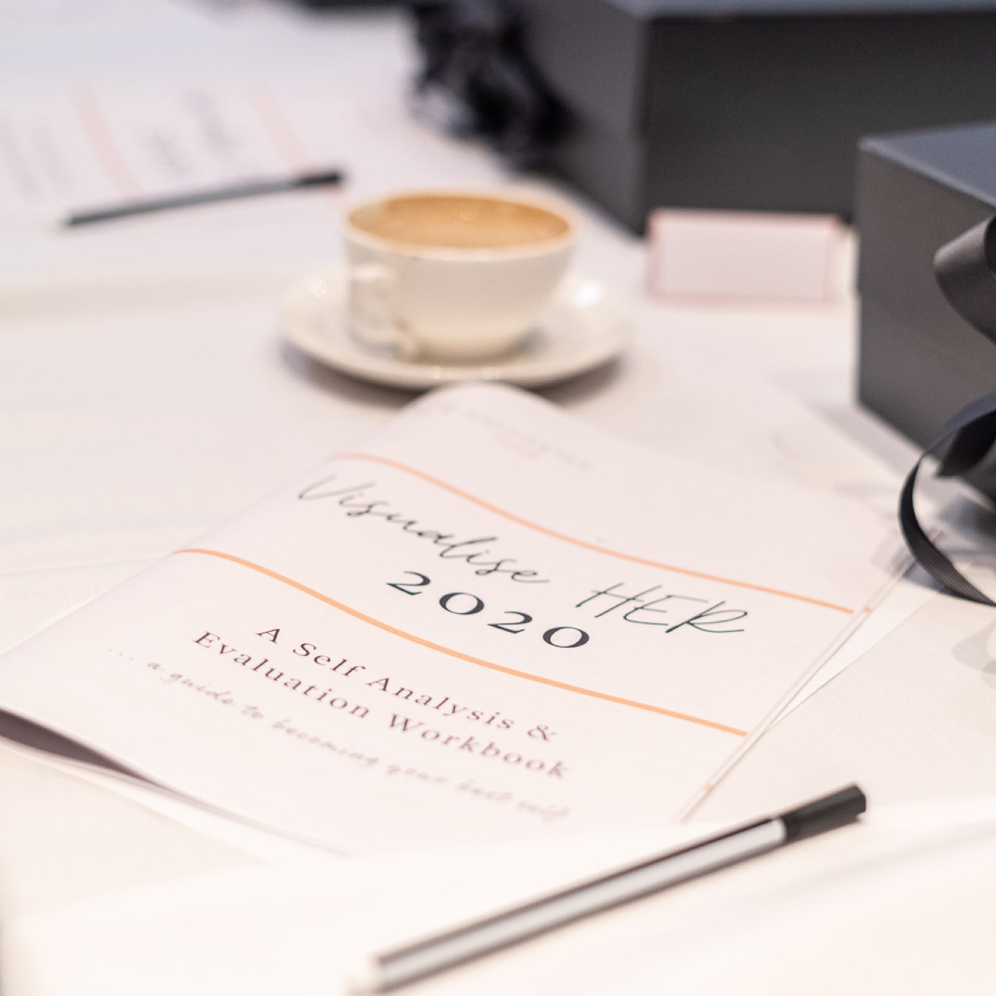 A Visualise HER 2020 self-reflection workbook beside a cup of coffee