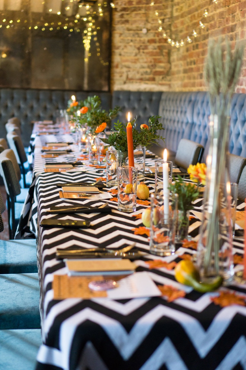 A candlelit long table set for a gathering under string lights