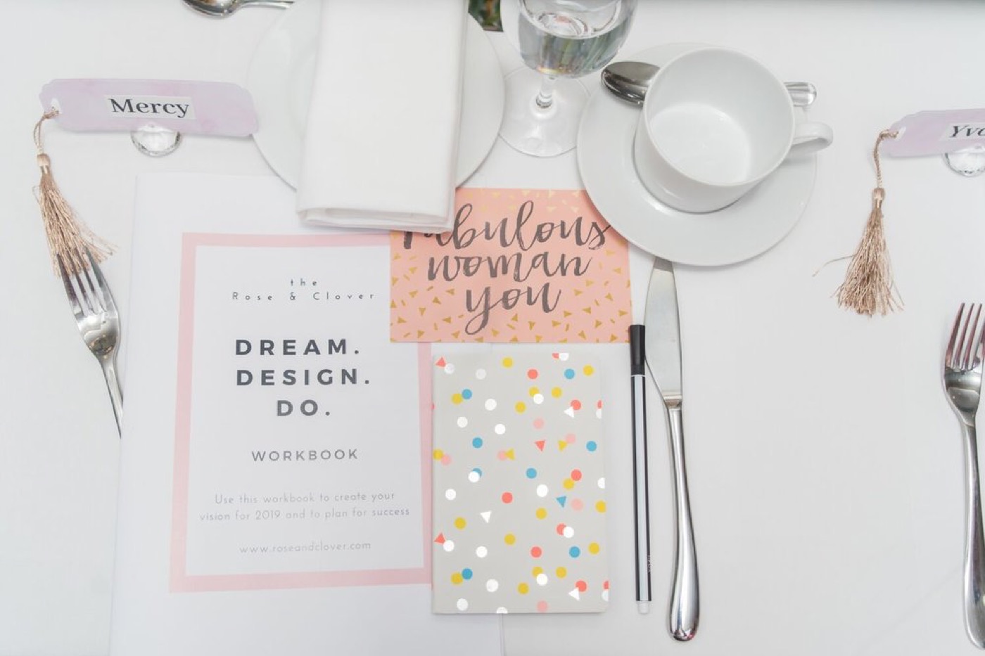 A styled table setting with a goal-setting workbook and place cards